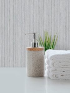 Ceramic shampoo, soap bottle and towels on counter over kitchen room background. White top table and copy space.